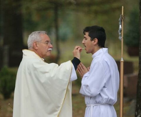 Bishop Anthony B. Taylor presents the Eucharist to Seminarian Pedro Alvarez at the All Souls Mass at Calvary Cemetery in Little Rock Nov. 2, 2021. CASA pays for a portion of the seminary tuition and living expenses for 25 diocesan seminarians.