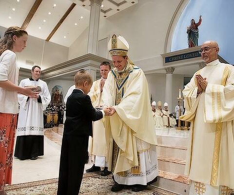 Bishop Pohlmeier accepts the gifts from his niece, Rose, and nephew, Damien, during the Liturgy of the Eucharist at his episcopal ordination, July 22.
