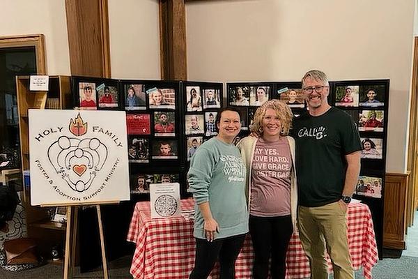 Sara Bridges stands with Camas and Matt Maroney at the ministry table at St. Stephen Church in Bentonville during ministry weekend in April 2022.