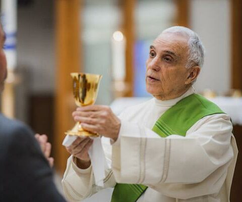 Deacon Chuck Marino demonstrates serving the blood of Christ during Mass Jan. 25, 2022, at St. Raphael Church in Springdale. Some parishes have been unable to resume offering Communion in both species because pandemic restrictions left them without enough eucharistic ministers 
to serve.
