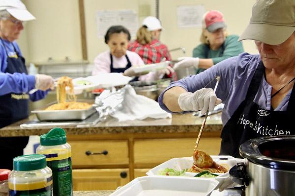 Sue Erb (right), a volunteer for Hope's Kitchen ministry at St. Mary Parish in Siloam Springs, helps prepare meals to be distributed March 3. Hope's Kitchen is celebrating 10 years of serving meals in the community.