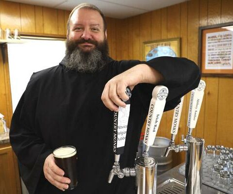 Brother Sebastian Richey, OSB, pulls a pint for a patron in the Country Monks taproom in May 2022. Even as the brewery expands into retail, Country Monks Brewing's physical location at Subiaco Abbey remains a popular gathering spot.