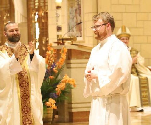 Cody Eveld of Charleston acknowledges the congregation May 19 at Subiaco Abbey after being presented for ordination to the diaconate by vocations director Father Jeff Hebert (left).