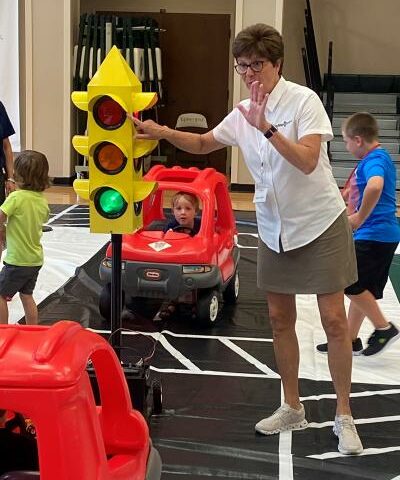 Safety Town founder Wendy Saer directs kids around a pretend town June 27 at Episcopal Collegiate School in Little Rock to teach them road safety in a fun and engaging manner.