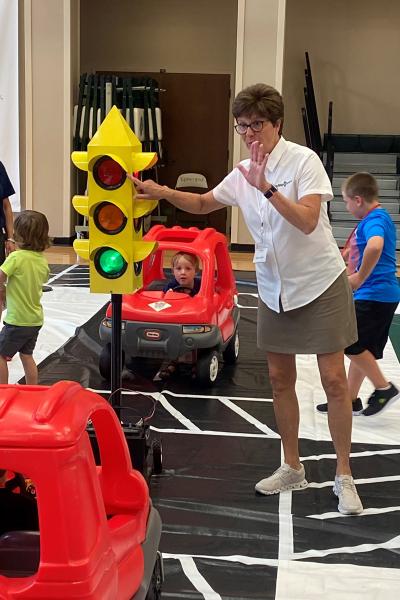 Safety Town founder Wendy Saer directs kids around a pretend town June 27 at Episcopal Collegiate School in Little Rock to teach them road safety in a fun and engaging manner.