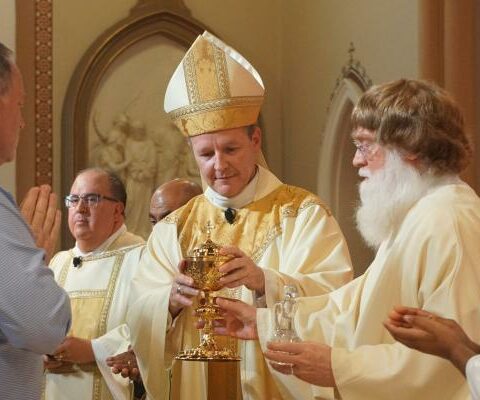 Bishop Erik Pohlmeier hands a chalice to Deacon Tom Parks of Rogers during the presentation of gifts at his 25th priestly anniversary Mass July 25 at the Cathedral of St. Andrew in Little Rock.
