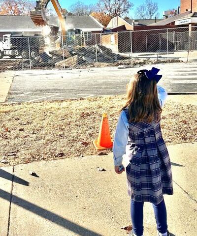 St. Vincent de Paul kindergarten student Olivia Mooney watches Nov. 15 as they begin digging up the parking lot to begin laying the foundation for the new junior high building in Rogers.