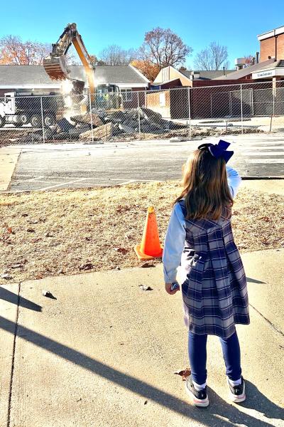 St. Vincent de Paul kindergarten student Olivia Mooney watches Nov. 15 as they begin digging up the parking lot to begin laying the foundation for the new junior high building in Rogers.