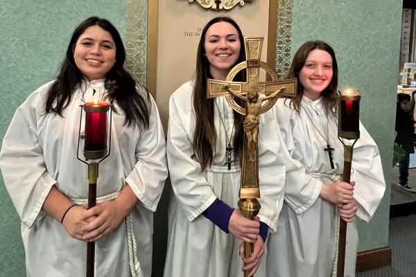 High school students Mandy Larios, Chloe Skinner and Marleigh Thessing serve as cross and candle bearers during Stations of the Cross Feb. 24, 
2023, at St. Joseph Church in Conway.